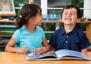 Two delighted kids enjoying a book at school. 